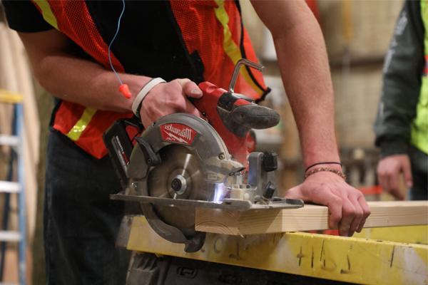 Student using a hand saw to cut wood